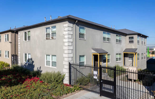 A grey building with a black fence and gate in front.