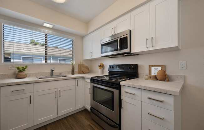 a kitchen with white cabinets and black appliances and a window