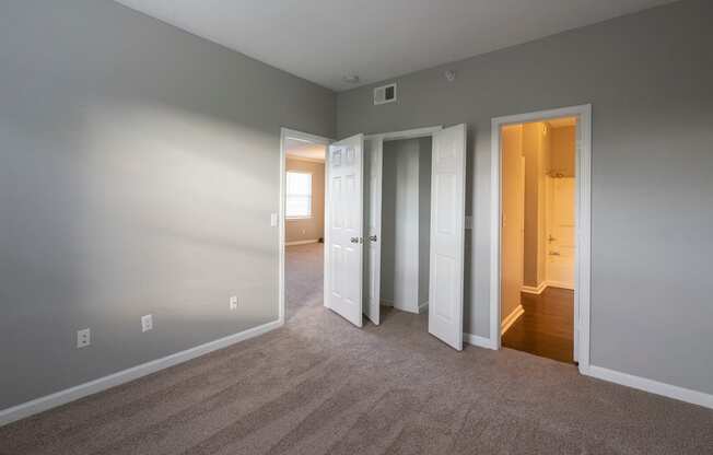a bedroom with three doors and a carpeted floor
