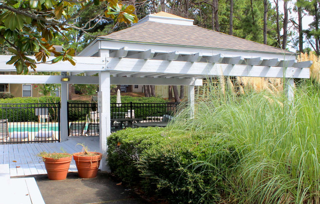 a white gazebo with plants in front of it