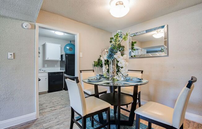 A dining room with a table set for two and a mirror above it.