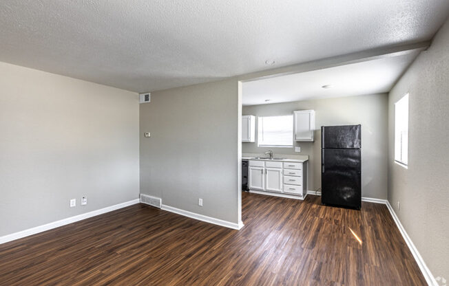 A room with wooden floors and a black fridge.