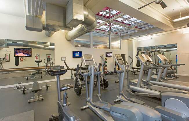 a gym with weights and cardio equipment and a tv
