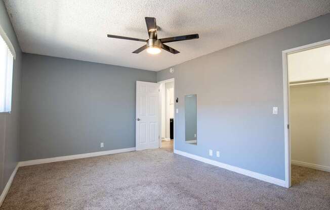 A room with a ceiling fan and carpeted floor.