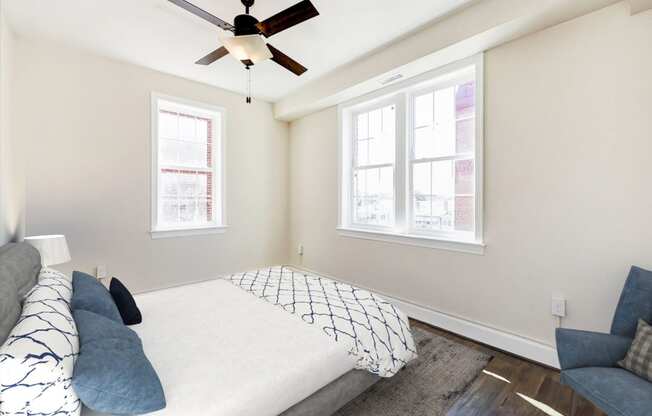 bedroom with bed, chair, large windows and ceiling fan at petworth station apartments in washington dc