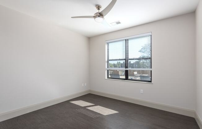 Hibernia bedroom with rich vinyl plank flooring, oversized windows with white blinds and ceiling fan