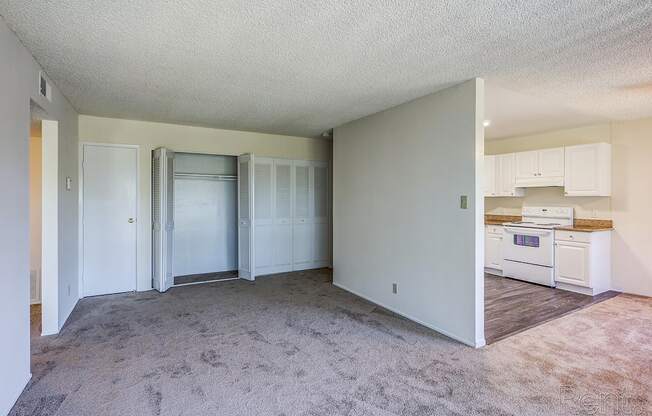 an empty living room with a kitchen in the background at Terrace View Apartments, Daly City