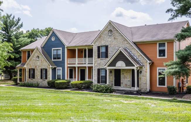 Dog-Friendly Apartments in Westerville, OH - Fairway Lakes - Property Exterior with Stone Details, Orange and Blue Walls, Private Balcony, and Lush Landscaping