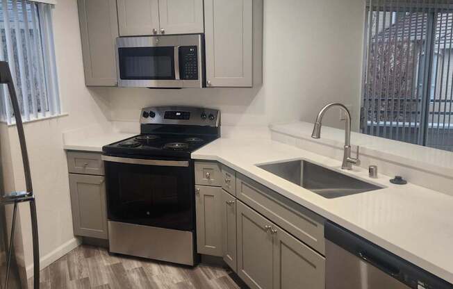 A kitchen with a stove, oven, sink, and microwave.