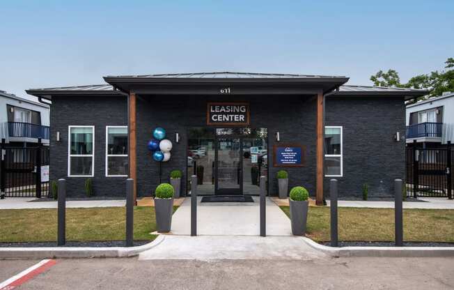 Leasing Center at Stadium 700 Apartments in Arlington, TX - a grey brick building with dark stained wood columns for awning