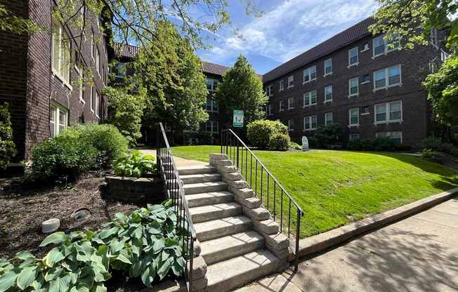 A set of stairs leads up to a grassy area in front of a brick building.