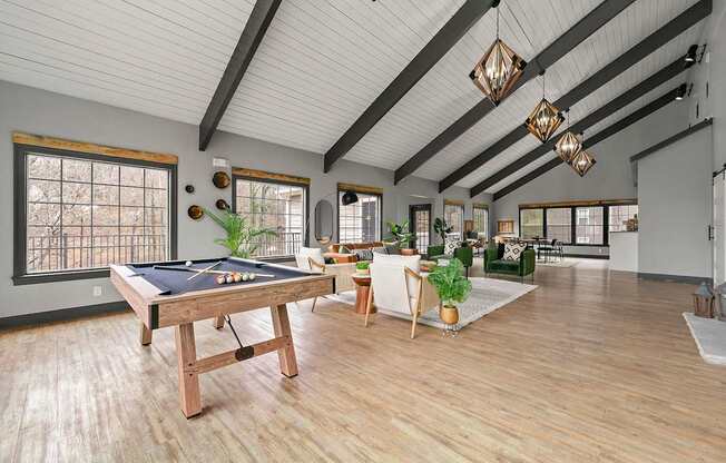 A billiard table is in the middle of a room with wooden floors and white walls.