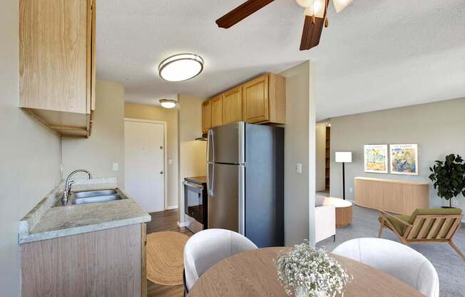 A kitchen with a refrigerator, sink, and dining table.
