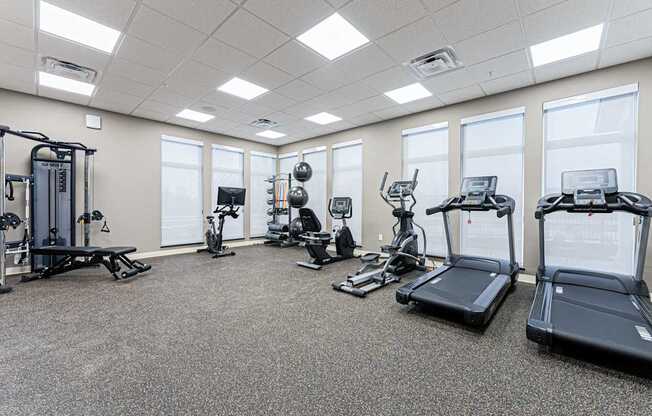 A spacious gym with a variety of equipment including treadmills, elliptical machines, and weight machines.