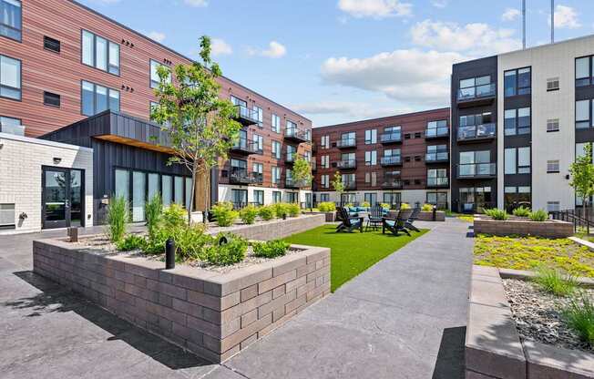 A modern building complex with a landscaped courtyard in the foreground.