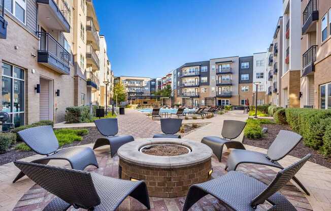 A patio with chairs and a fire pit in the middle of a courtyard.