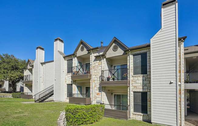 Row of our apartment buildings with balconies and a clear blue sky at On the Green apartments in Austin, TX