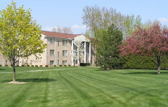 a large brick building with a red roof and a pink flowering tree in front of it