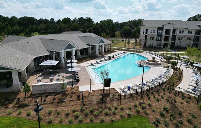 A large outdoor swimming pool surrounded by a black fence and a building in the background.