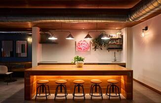 A bar with a wooden counter and four stools.