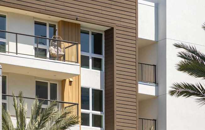 A modern building with a balcony and palm trees in front. at Elements Apartments*, California