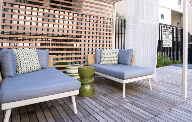 Two chairs with cushions and a table on a wooden deck.