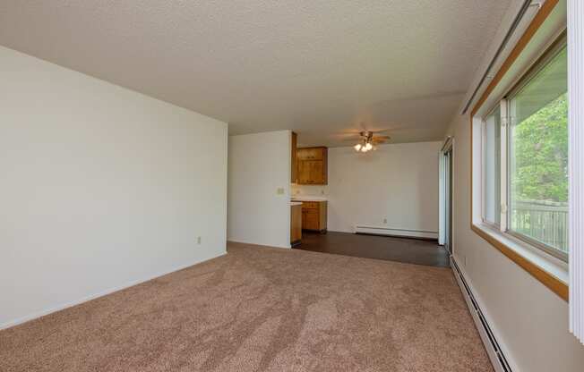 an empty living room with a large window and carpet. Fargo, ND Country Club Apartments.