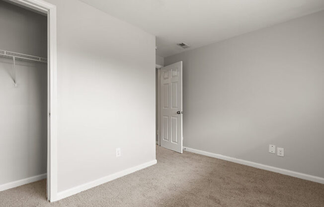 an empty bedroom with a door to a closet
