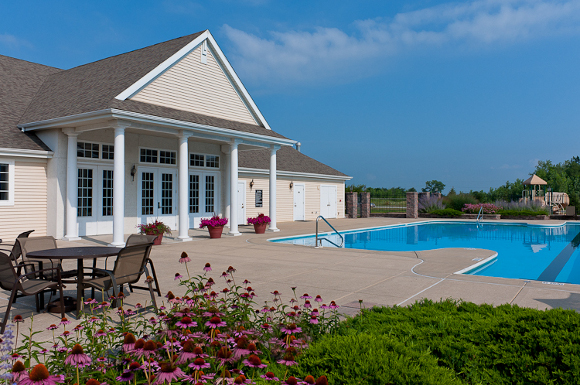 Heated outdoor Olympic swimming pool with lavish sundeck, and dining table at Prairie Point apartments.