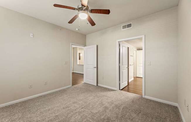 A room with a ceiling fan and carpeted floor.