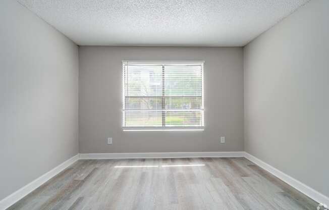 an empty room with wood floors and a window