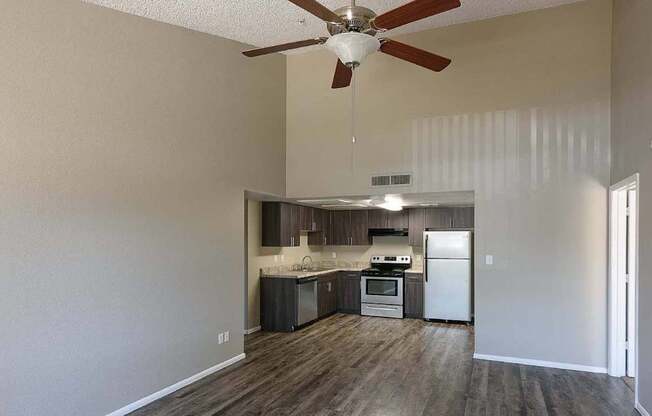 A kitchen with a refrigerator, oven, and sink is visible from the living room.