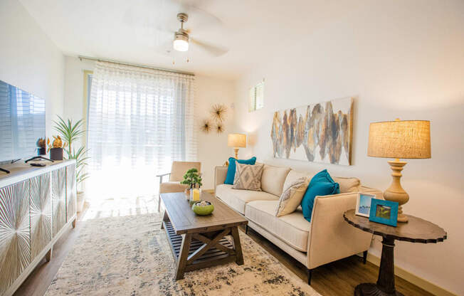 Apartments in Gilbert, AZ for Rent - Curve At Gilbert - Living Room With A Ceiling Fan, Plank Flooring, And A Sliding Glass Door To A Private Patio/Balcony