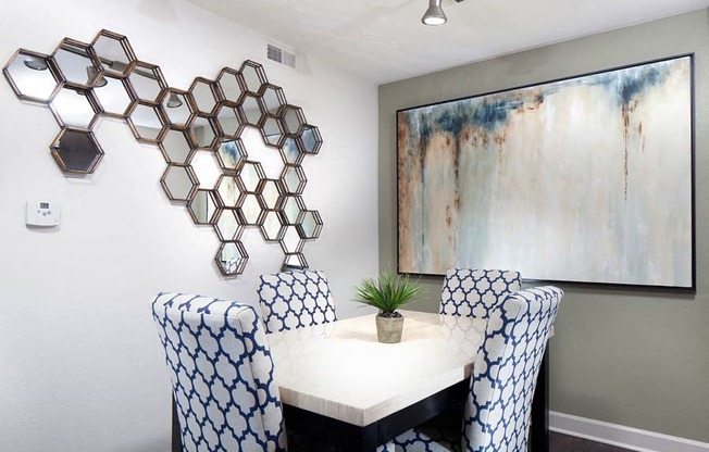 Ardenne Apartments Dining room with white table, blue and white chairs, grey walls and mirror art