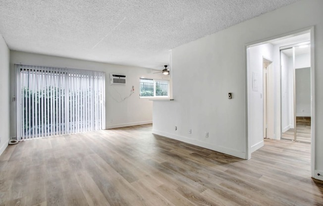 an empty living room with hardwood floors and a large window