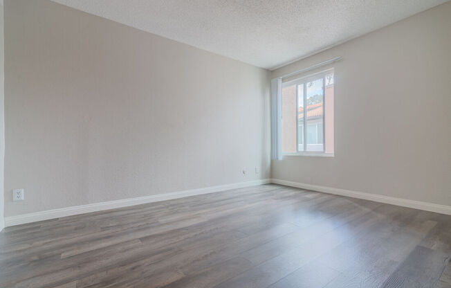 an empty living room with wood floors and a window at City View Apartments at Warner Center, California