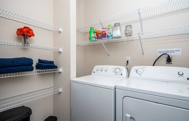 Laundry room with full-size washer and dryer and built-in shelving at Riverstone apartments for rent in Macon, GA