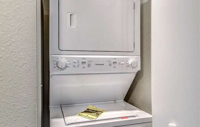 A white dishwasher is installed in a narrow space between a wall and a door.
