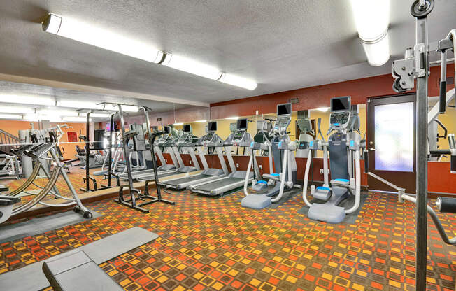 A gym with a variety of equipment including treadmills, weights, and exercise machines.