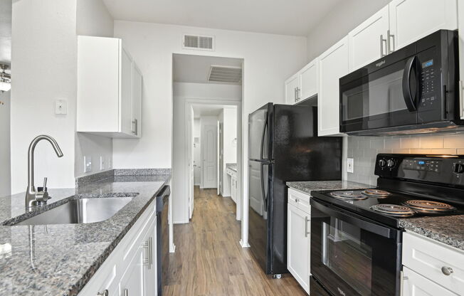 A kitchen with black appliances and white cabinets.