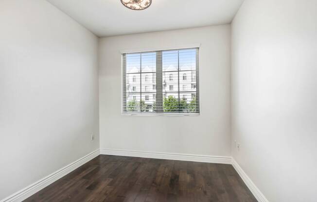 an empty living room with a window and hardwood floors