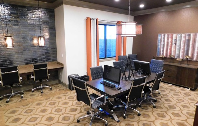 a conference room with a table with computers and chairs