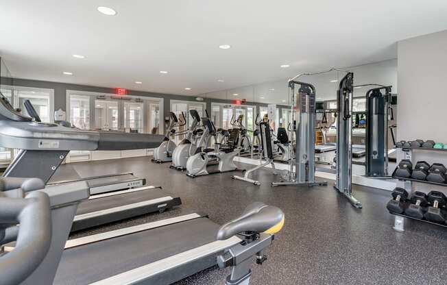 a gym with cardio equipment and weights in a building with windows at Pier Village Apartments, Long Branch, 07740