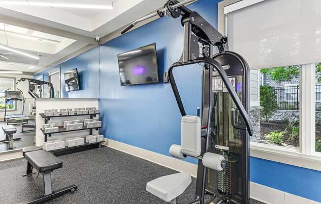 A gym with a blue wall and a television mounted on it.