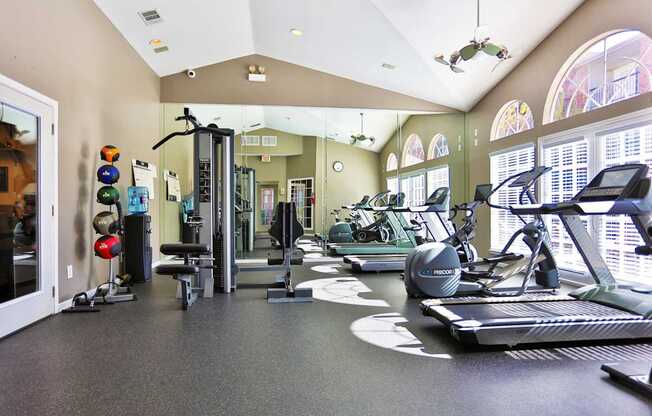 A gym with a variety of equipment including treadmills, weights, and exercise machines at The Inverness Apartments in Houston, TX