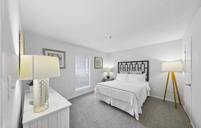 A bedroom with a bed, nightstand, and two lamps.