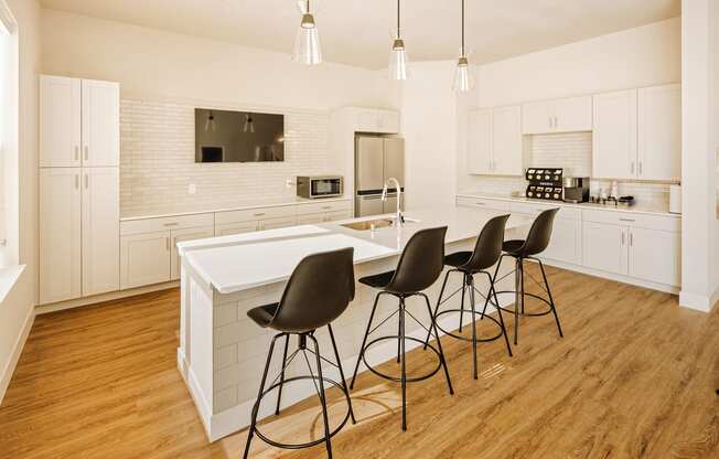a large white kitchen with a white island and black chairs at 44 West Luxury Living, Valley Park