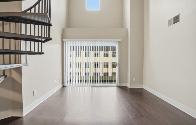 A room with a wooden floor and a balcony with a railing.