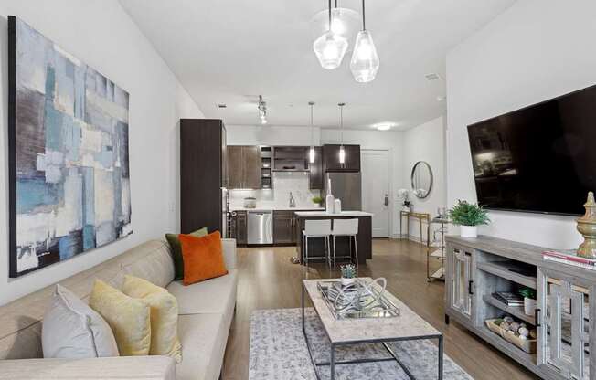 A modern living room with a large painting on the wall and a white sofa with orange and yellow pillows at Knox Heights Apartments in Dallas, TX