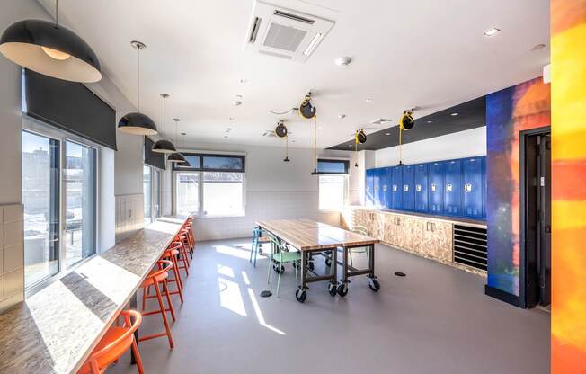 A room with a long table and chairs on the left side and a wall with a colorful mural on the right side.
